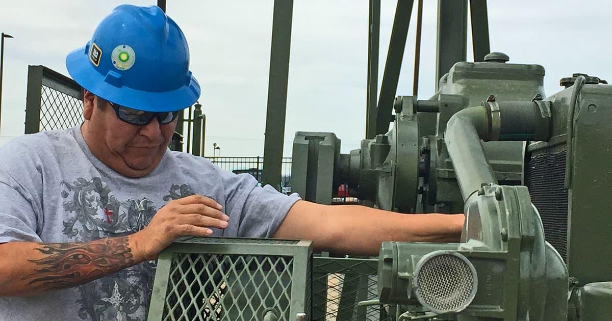 一名男子，戴着蓝色安全帽，在石油和天然气设备上工作.